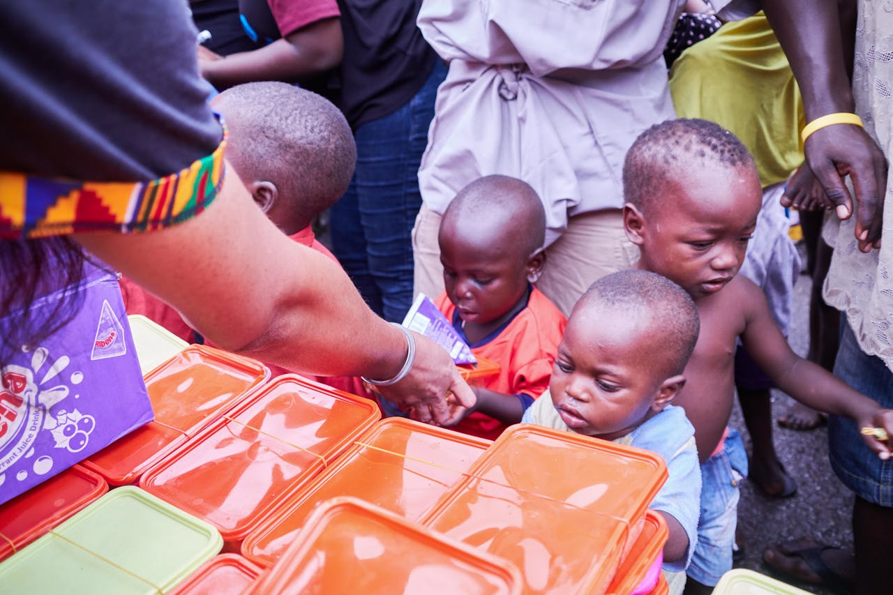 about-01 Young children receiving essential supplies from volunteers during a distribution event.