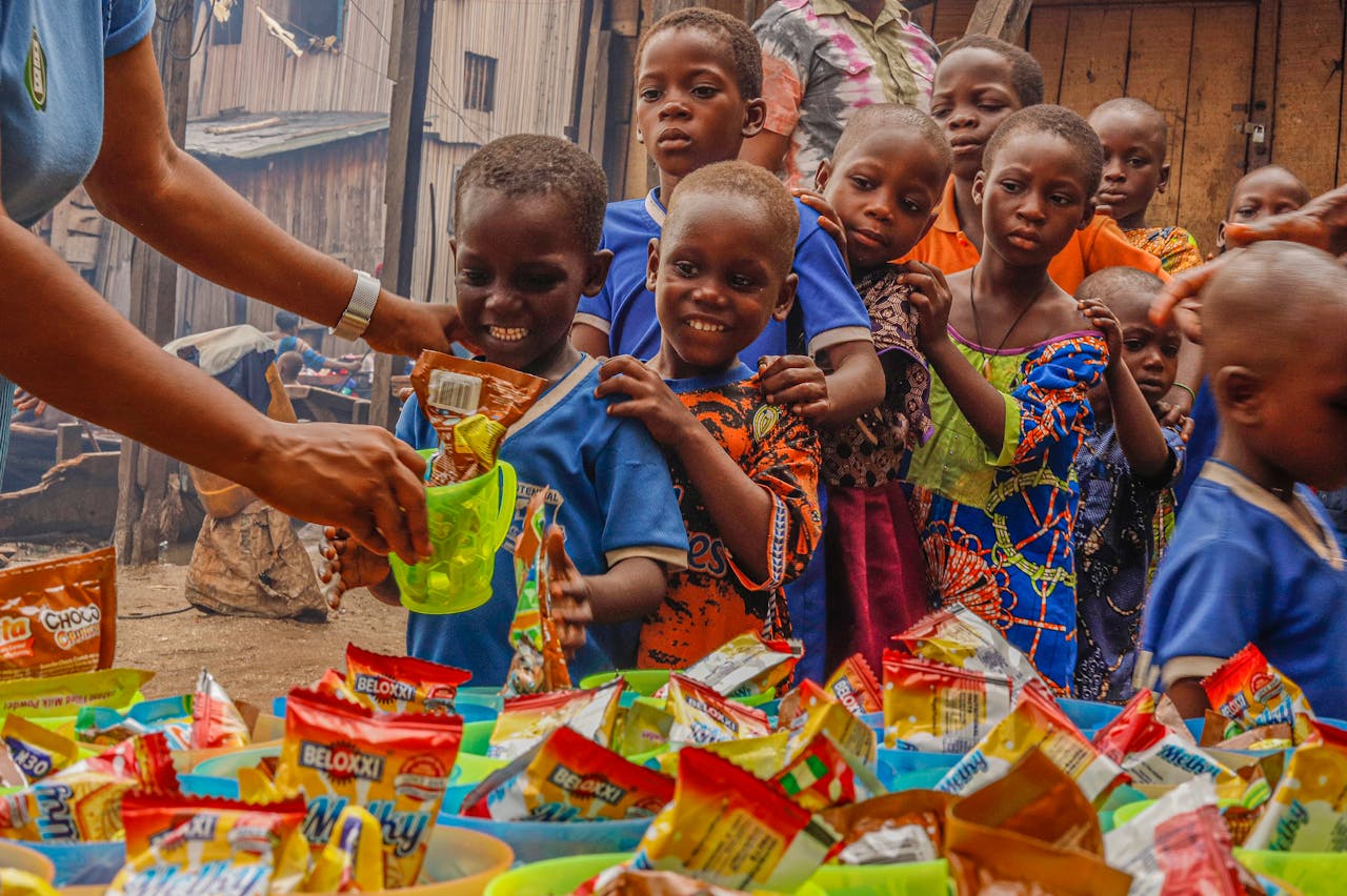 hero-img-02 Joyful children receiving food supplies from a volunteer in an outdoor setting.